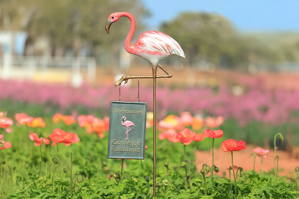 A staked garden sign of a flamingo that says "Welcome! Come be fabulous."