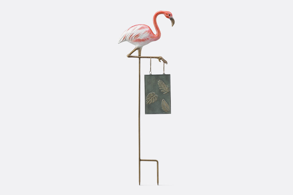 A staked garden sign of a flamingo that says "Welcome! Come be fabulous."