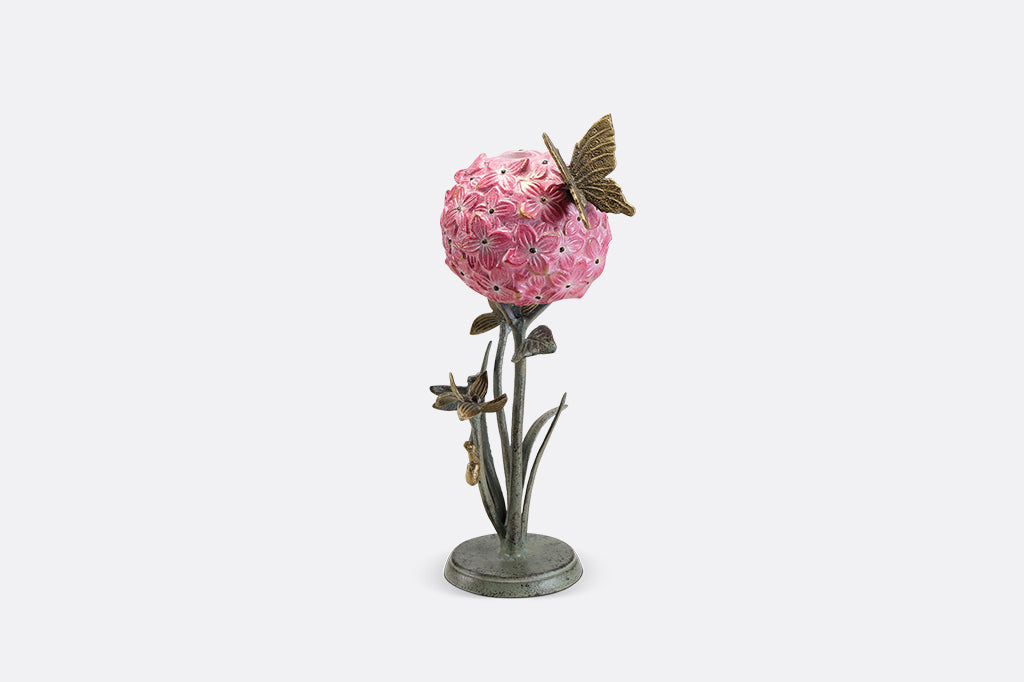 A single taper candleholder of a hydrangea blossom surrounded by a butterfly, dragonfly, and a snail.