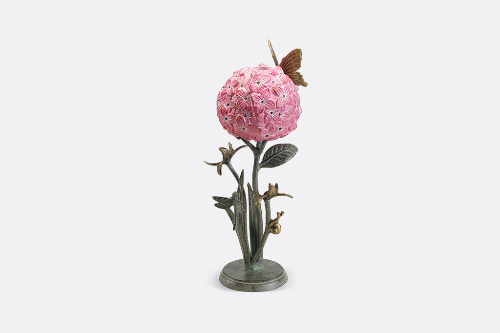 A single taper candleholder of a hydrangea blossom surrounded by a butterfly, dragonfly, and a snail.