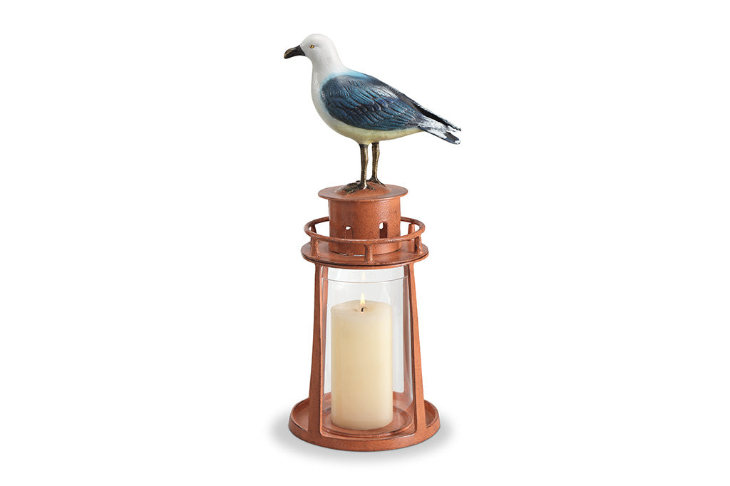 Candle lantern with a seagull perched on top against a white background