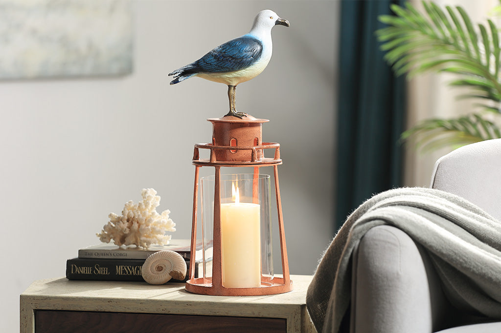 Decorative seagull on a lantern with a candle, placed on a table in a home setting.