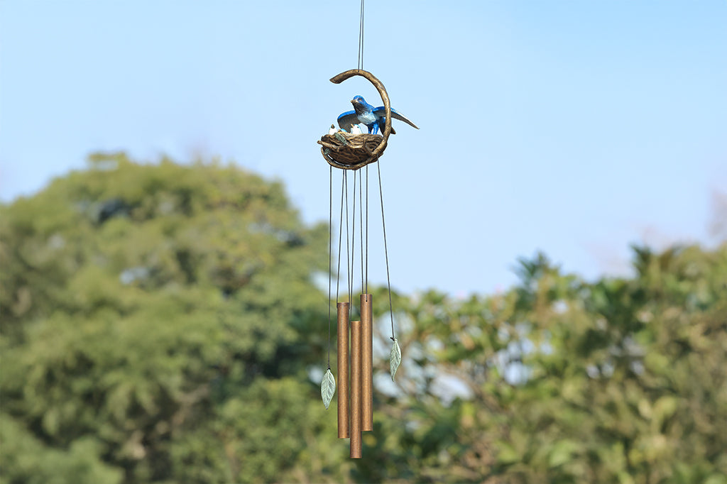 A windchime sculpture featuring a mama blue bird watching over her babies in their nest.