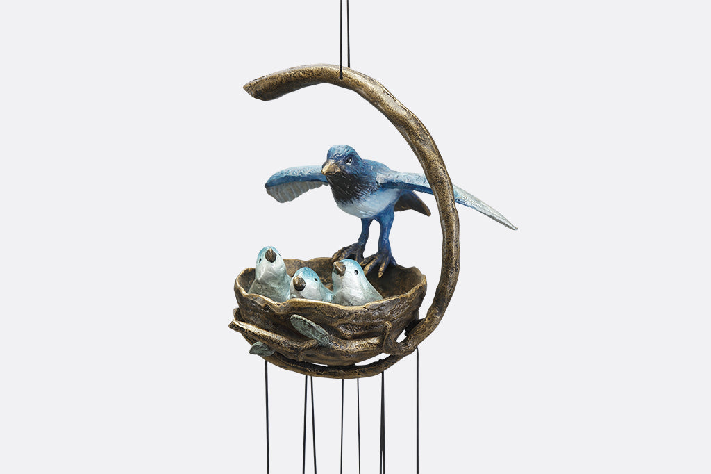 A windchime sculpture featuring a mama blue bird watching over her babies in their nest.