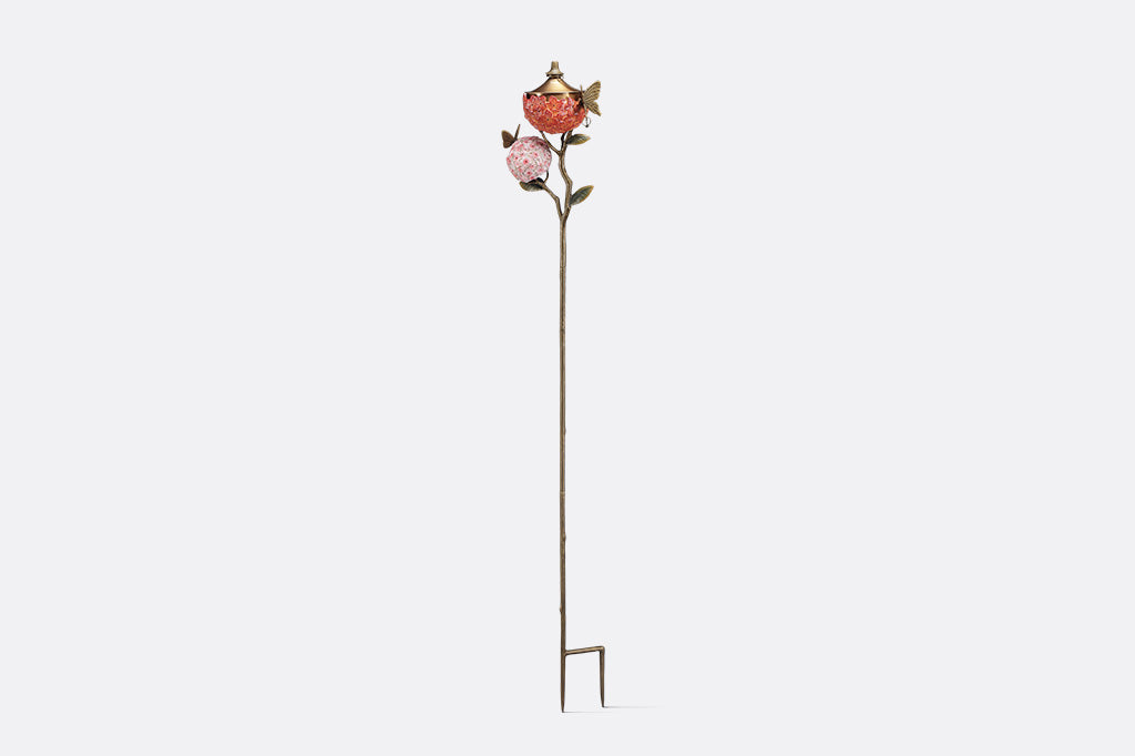 Decorative garden stake holding a candle with floral design on a white background