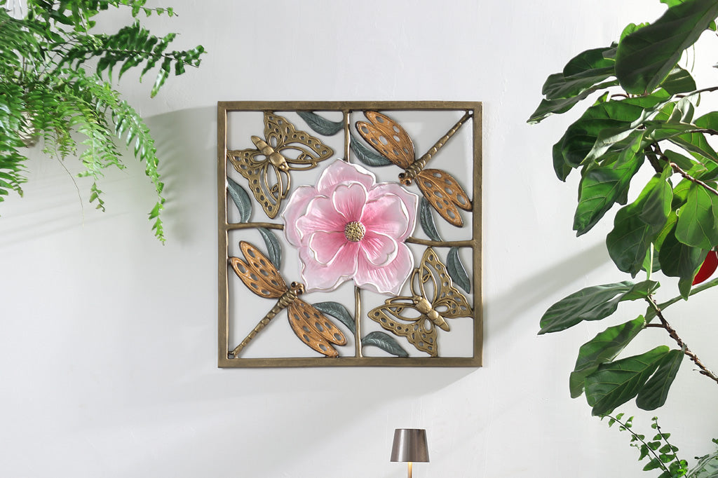 Decorative wall art with butterflies and a pink flower on a white wall with plants around.