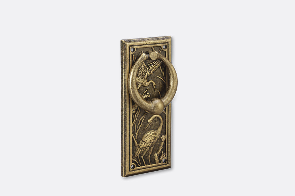 A doorknocker with embossed cranes and wildlife.
