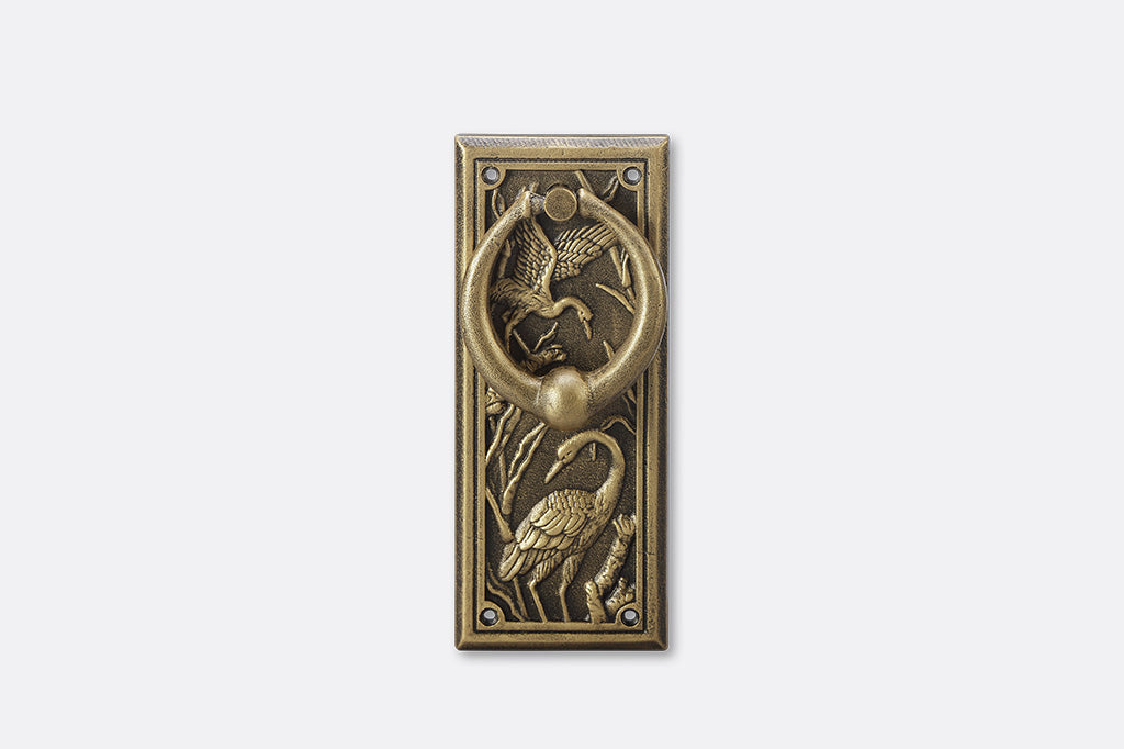 A doorknocker with embossed cranes and wildlife.