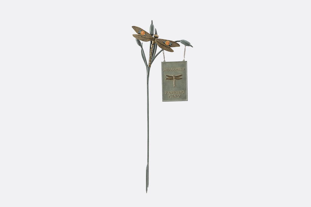 Decorative metal stake with dragonfly design on a white background