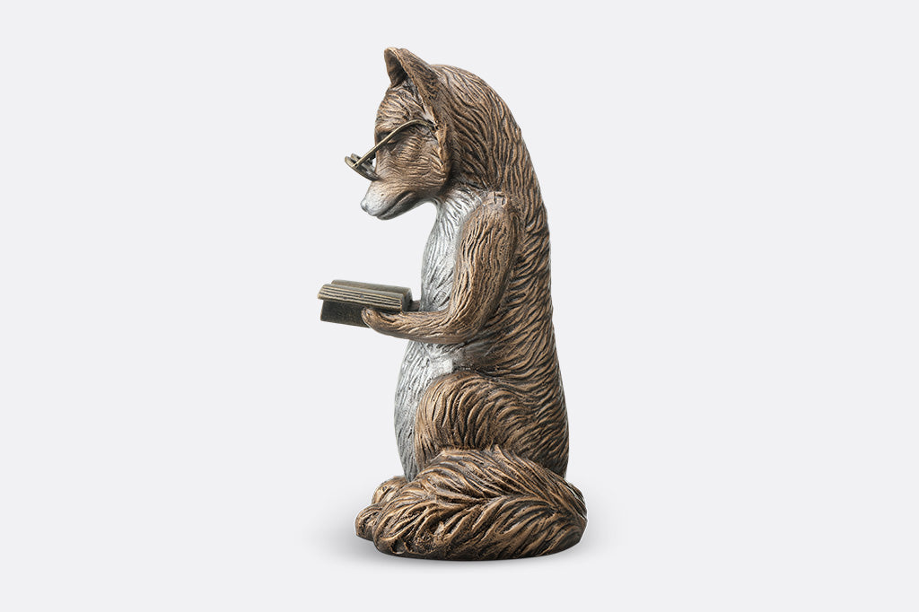 Statue of a fox holding a book on a white background