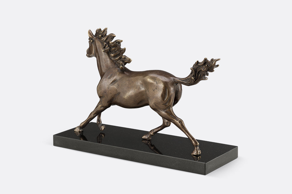 Brass sculpture of a horse running on a marble base.