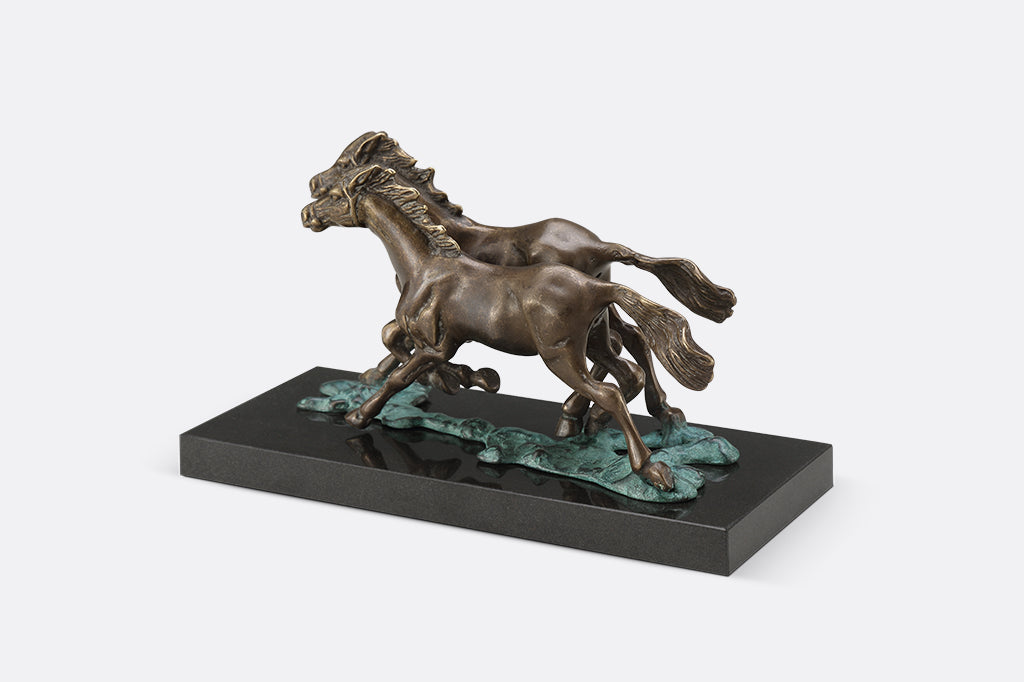 Brass sculpture of two horses running on water on a marble base.