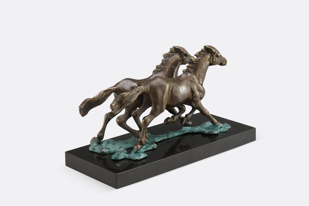 Brass sculpture of two horses running on water on a marble base.