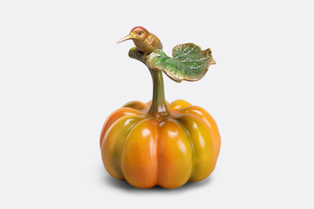 Decorative pumpkin with a bird on top against a white background