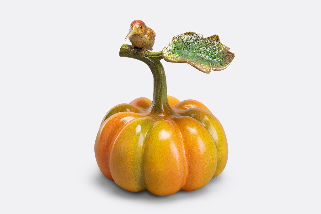Decorative pumpkin with a bird on top against a white background