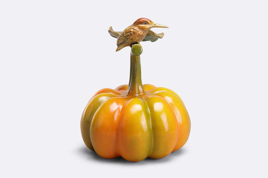 Decorative pumpkin with a bird perched on top against a white background