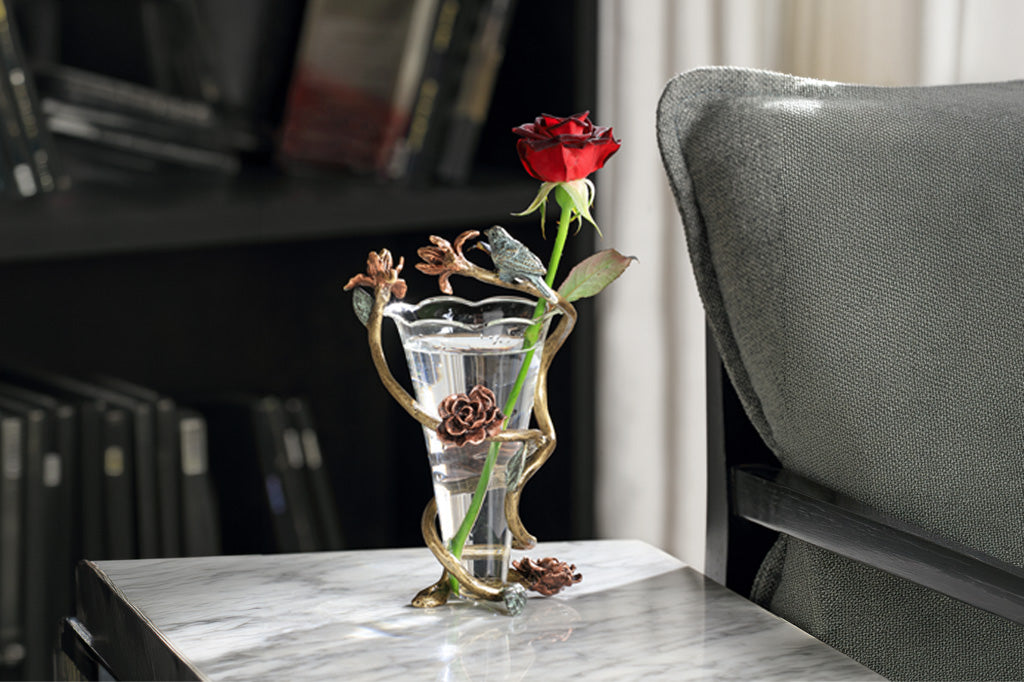 Rose inside glass vase with aluminum flower like detail surrounding vase with small bird sculpture attached 
