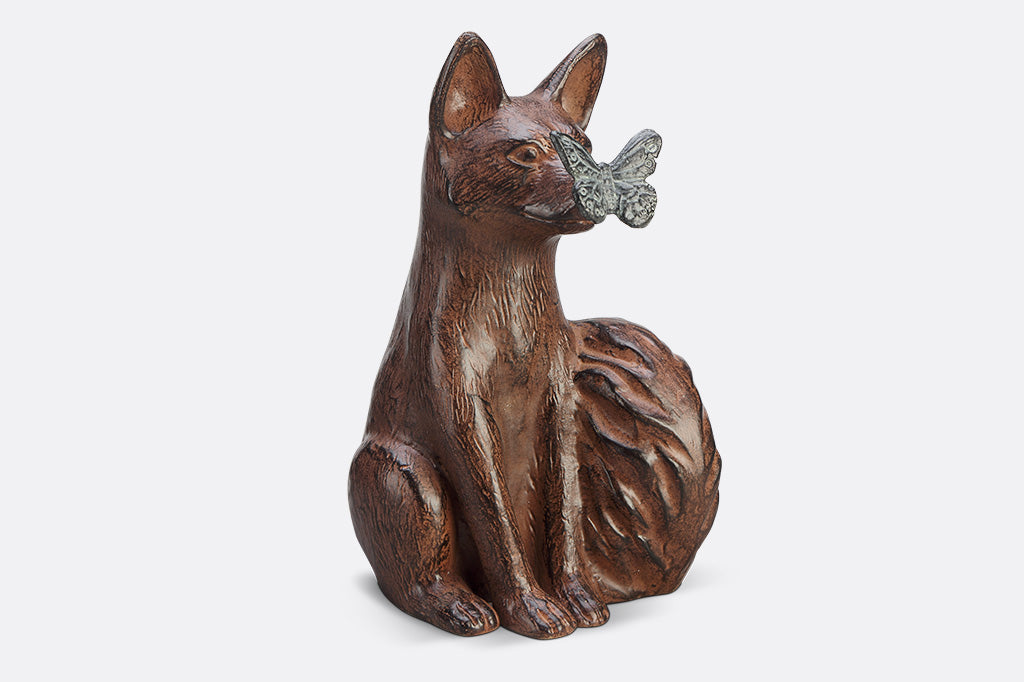 A sculpture of a blue butterfly landing on the nose of a fox.