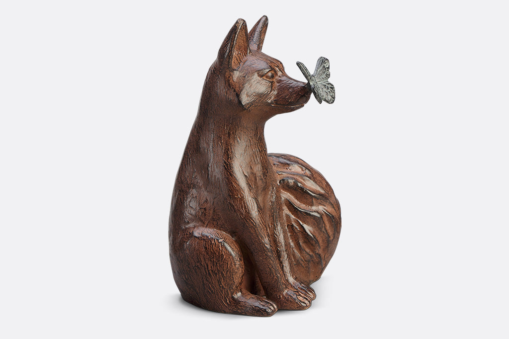A sculpture of a blue butterfly landing on the nose of a fox.