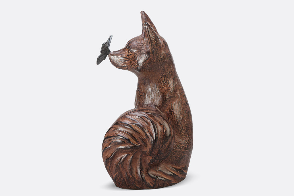 A sculpture of a blue butterfly landing on the nose of a fox.