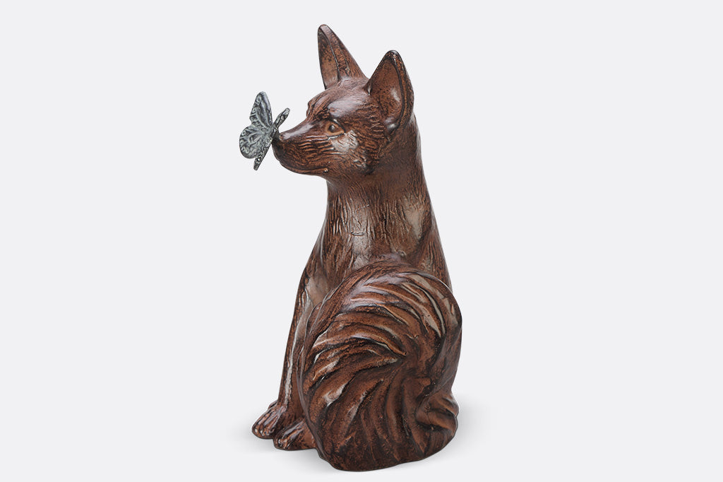 A sculpture of a blue butterfly landing on the nose of a fox.