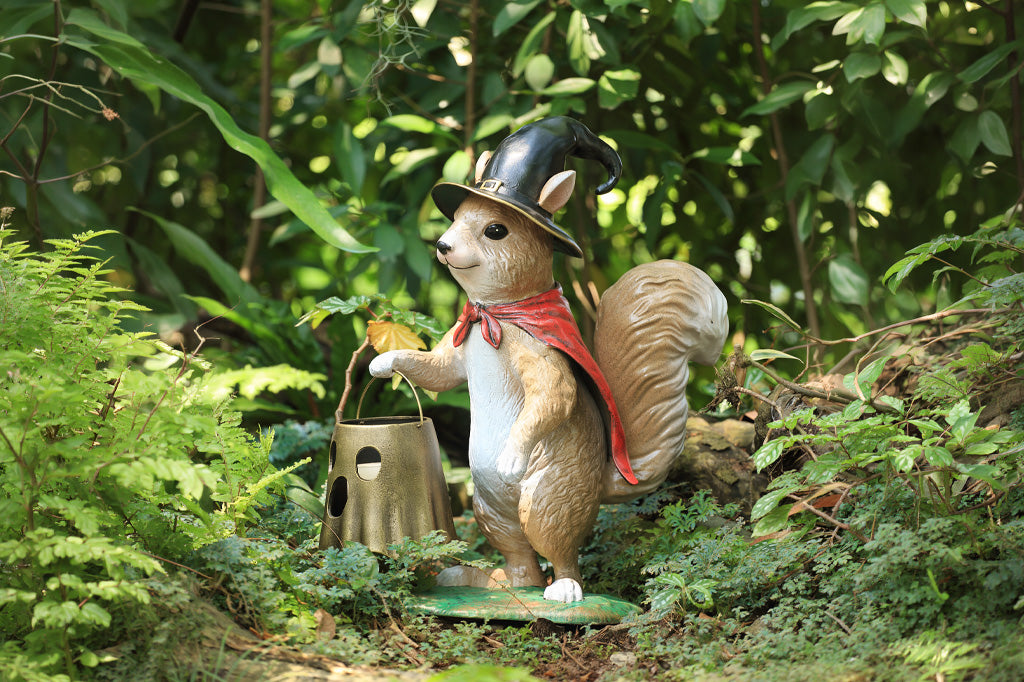 Decorative squirrel figurine with a top hat and red scarf in a forest setting