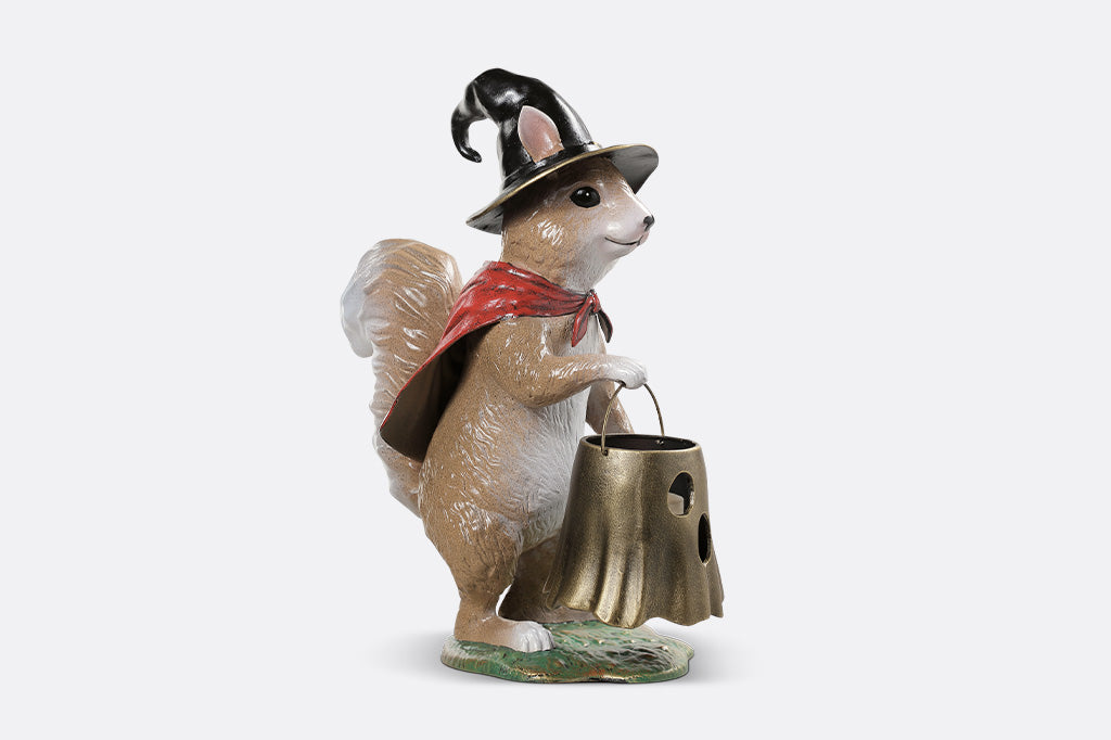 Squirrel figurine with a hat and red scarf holding a gold bucket on a white background