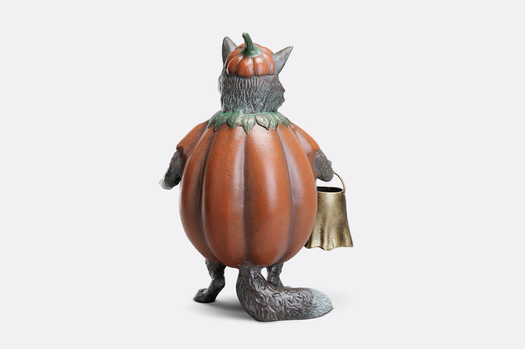 Cat figurine in a pumpkin costume with a basket on a white background