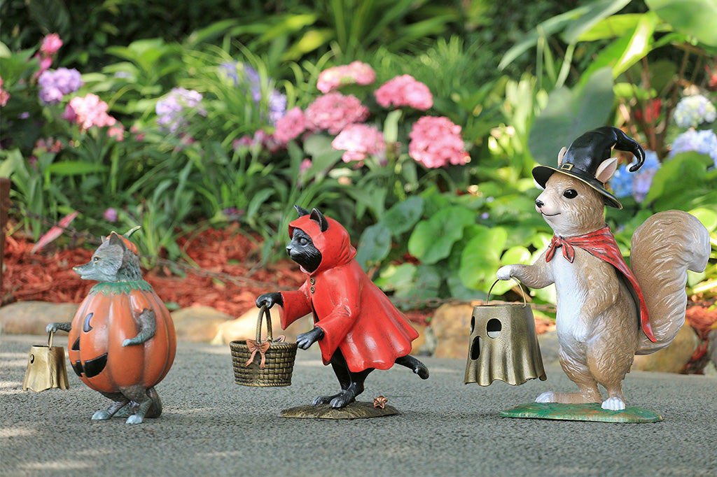 Three animated squirrel figurines in a garden setting with flowers and plants.