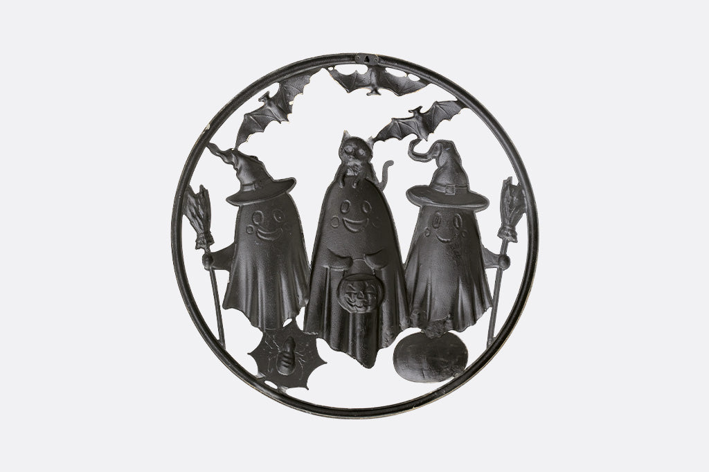 Decorative metal wall art with three ghost figures on a white background