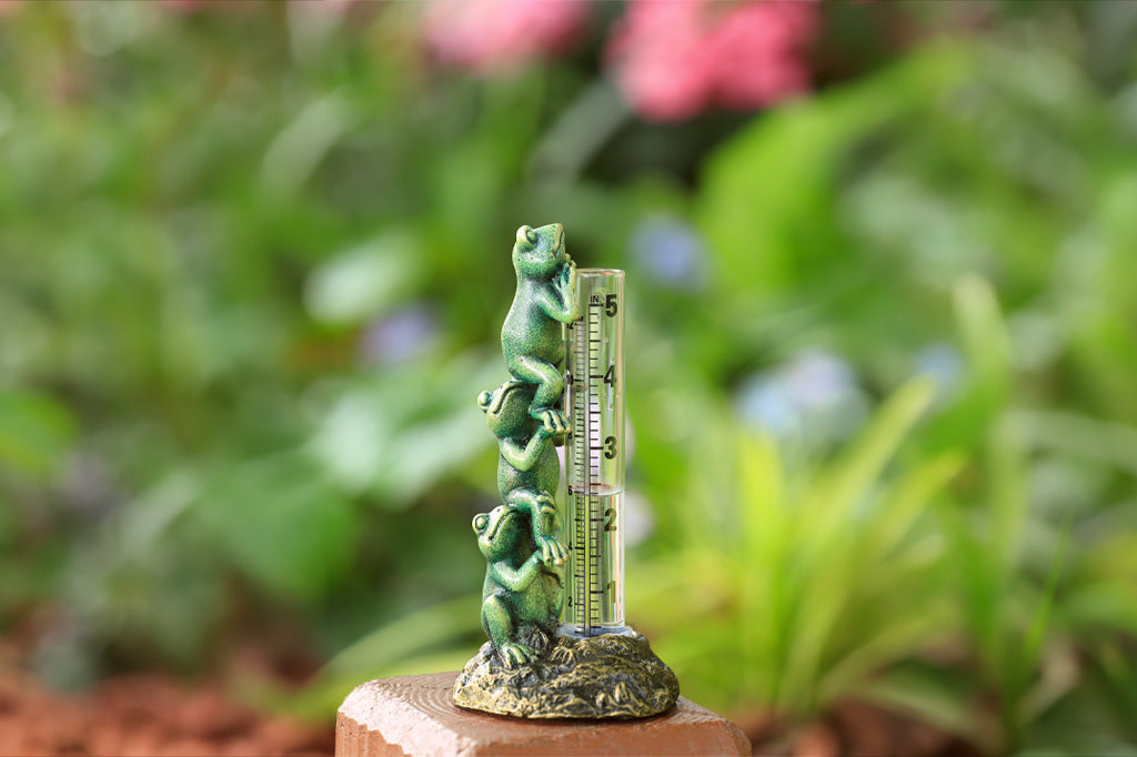 Decorative thermometer with a green frog design on a blurred natural background