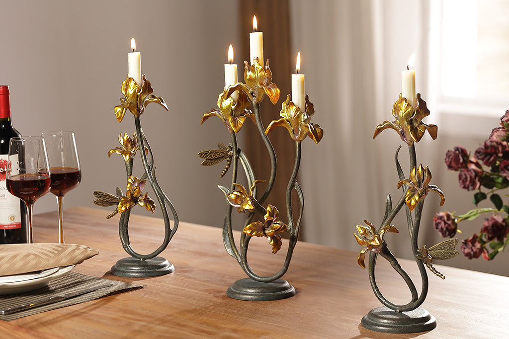 A pair of taper candleholders and a triple candleholder, all shaped like iris flowers with a dragonfly.