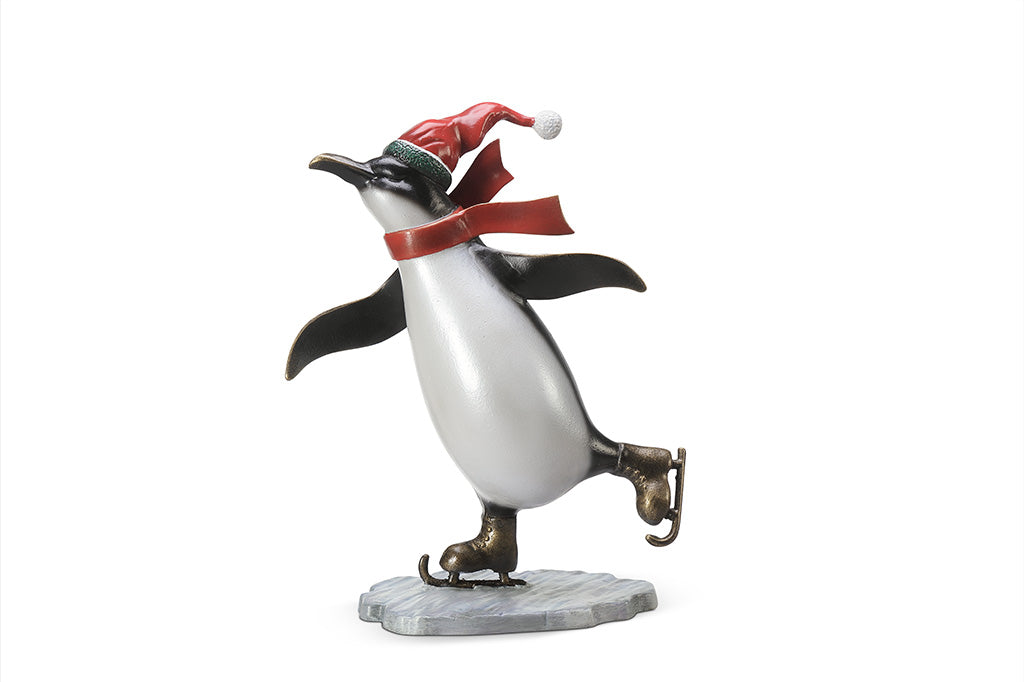 A sculpture of a penguin wearing a scarf and Santa hat ice skating.