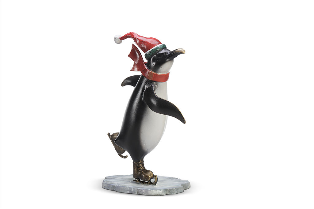 A sculpture of a penguin wearing a scarf and Santa hat ice skating.