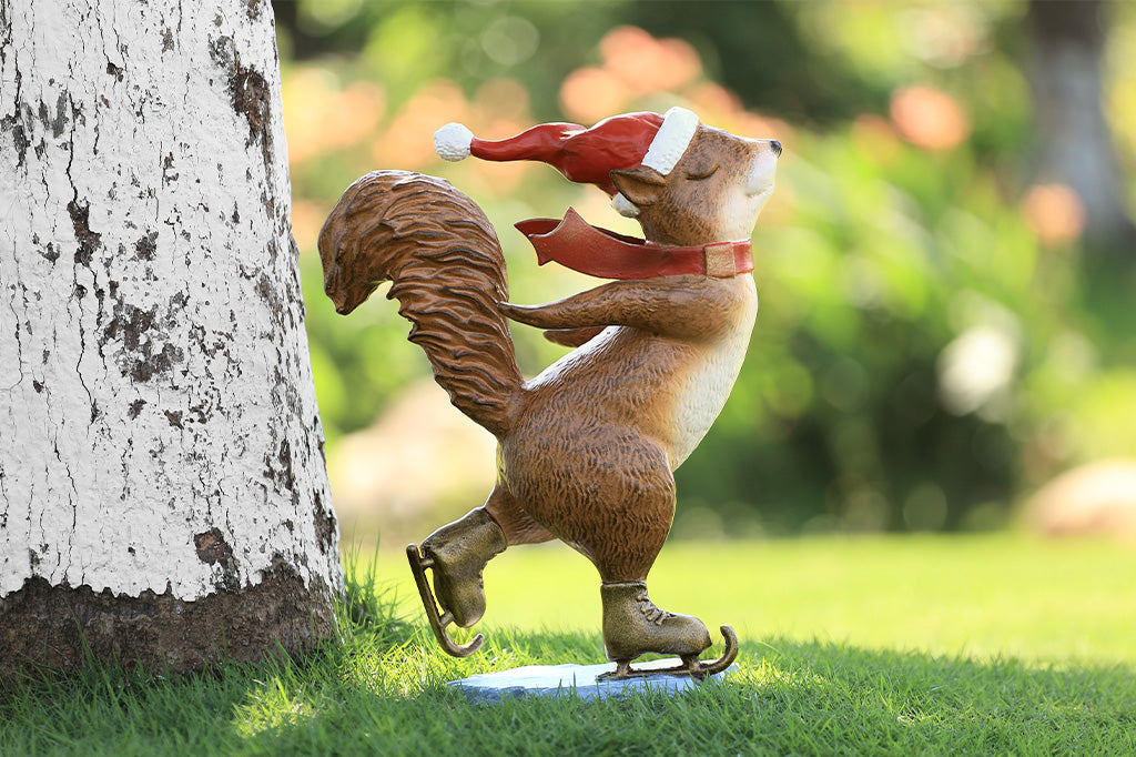 A statue of a squirrel wearing a santa hat and scarf ice skating.