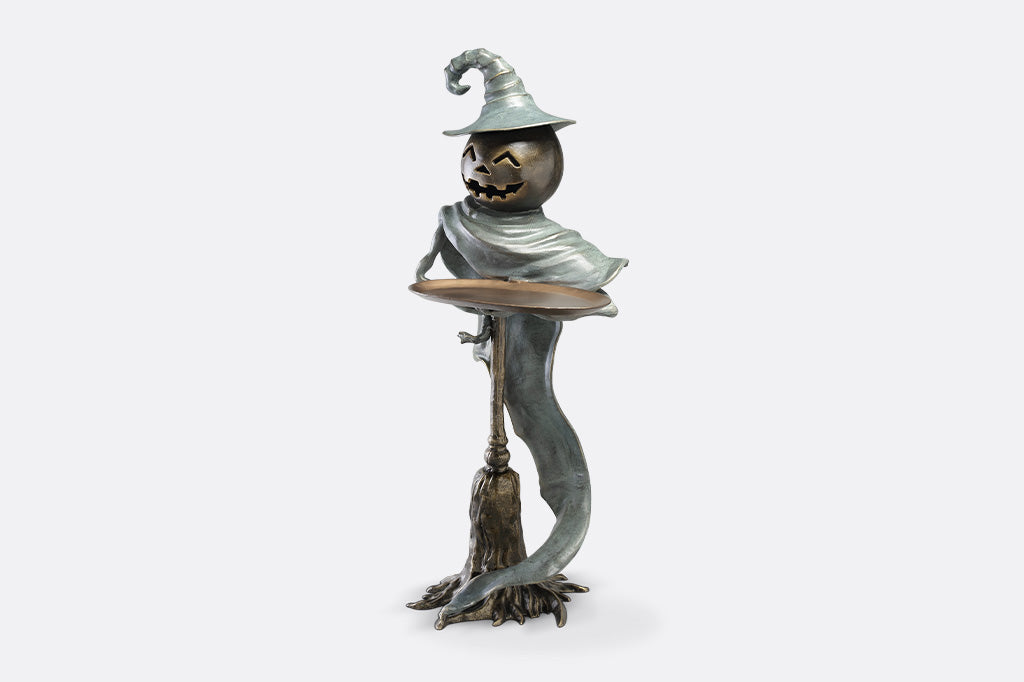 Halloween-themed figurine with a pumpkin head, hat, and broom on a white background