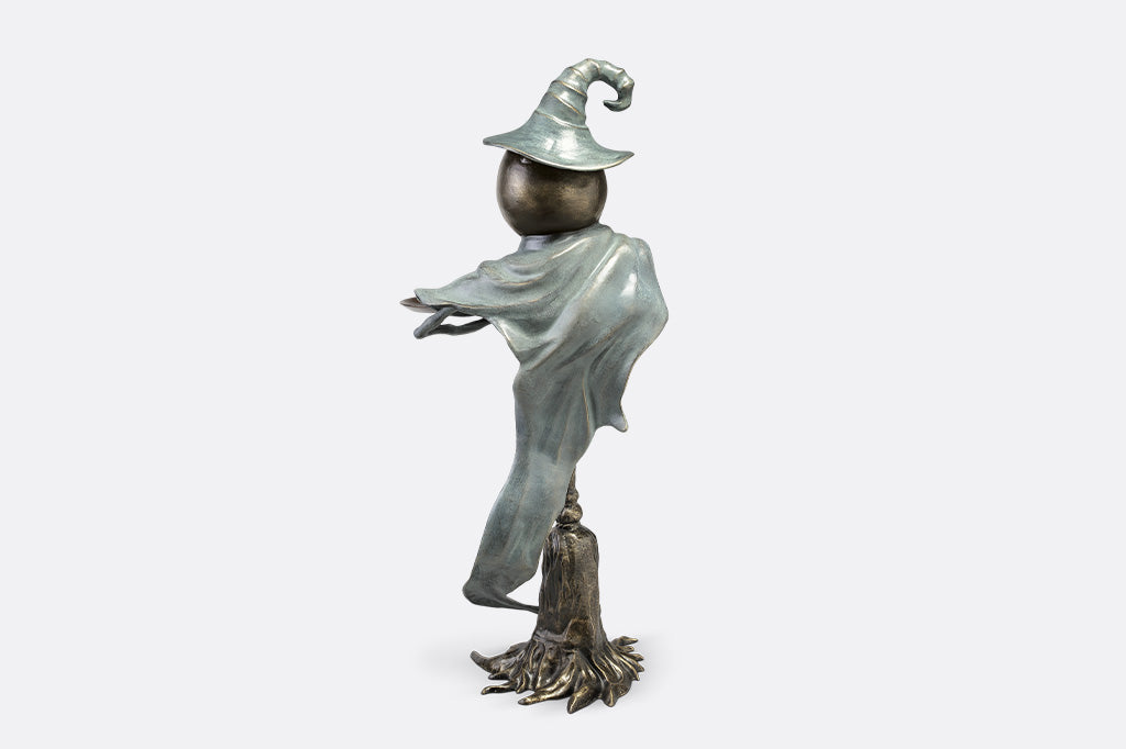 Statue of a figure in a pointed hat and flowing garment on a white background