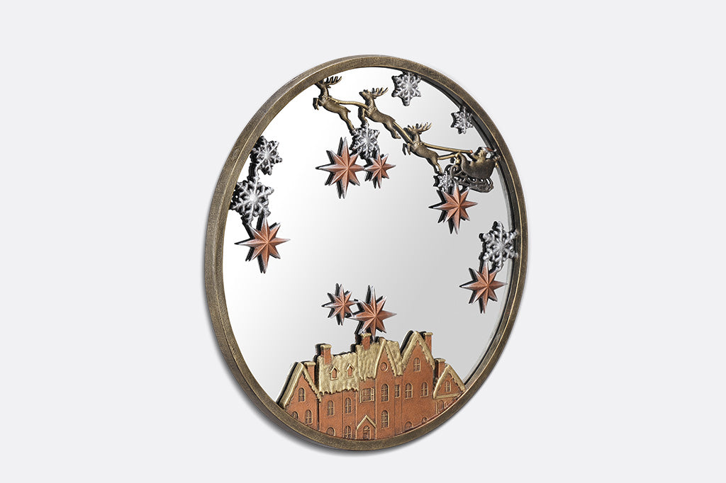 A round mirror with details of Santa and his sleigh being pulled by reindeer across a sky of stars and over rooftops.