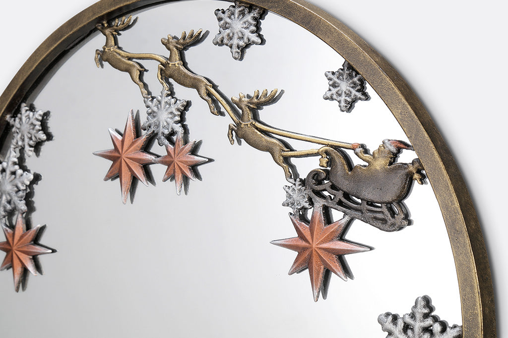 A round mirror with details of Santa and his sleigh being pulled by reindeer across a sky of stars and over rooftops.
