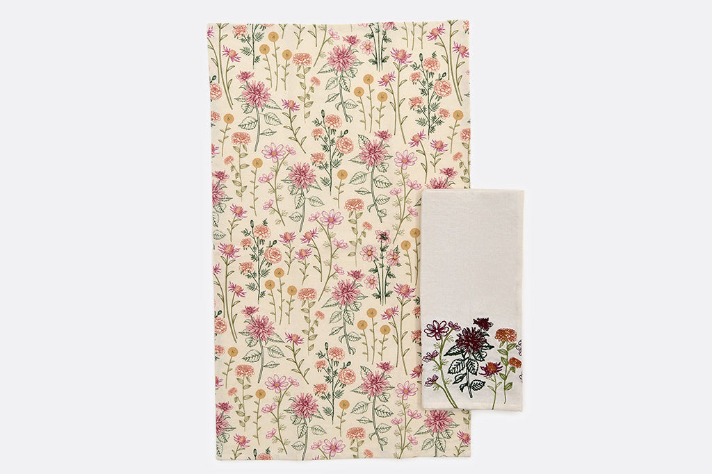 Two towels with detailed images of flowers. One folded, the other spread out.