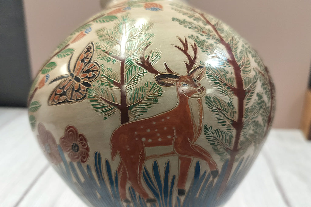 Close up view of deer design on the hand-etched wood fired clay pottery, Fair Trade from Nicaragua featuring forest animals