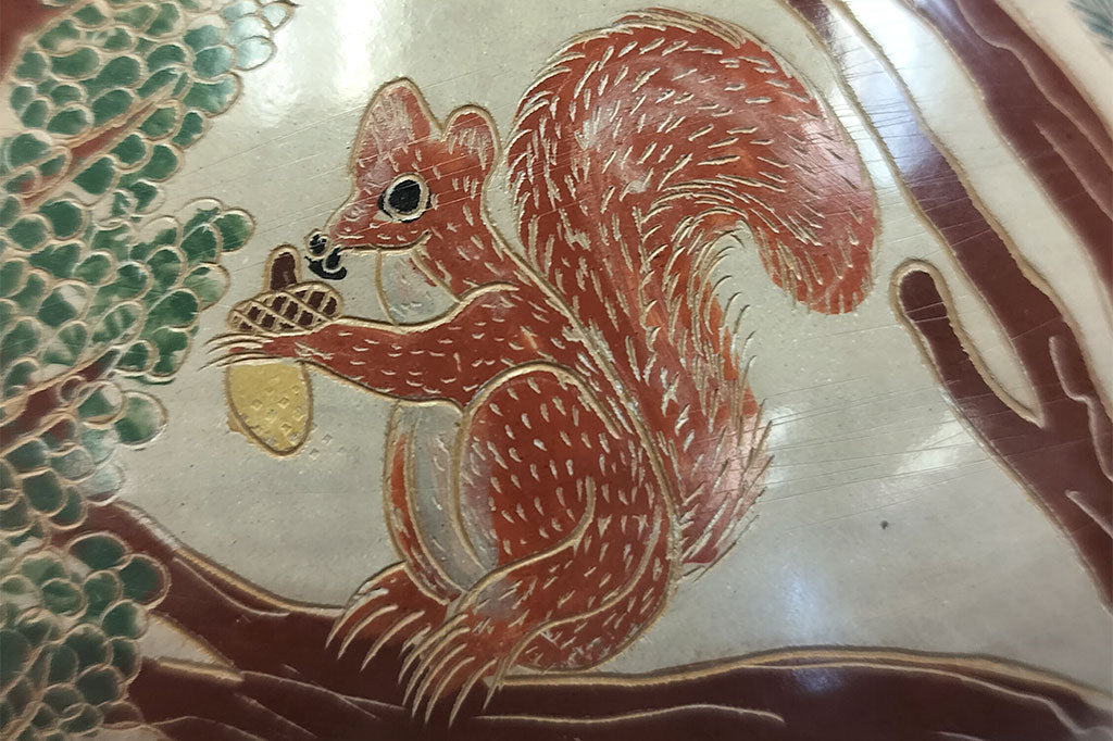 Close up view of squirrel design on the hand-etched wood fired clay pottery, Fair Trade from Nicaragua featuring forest animals