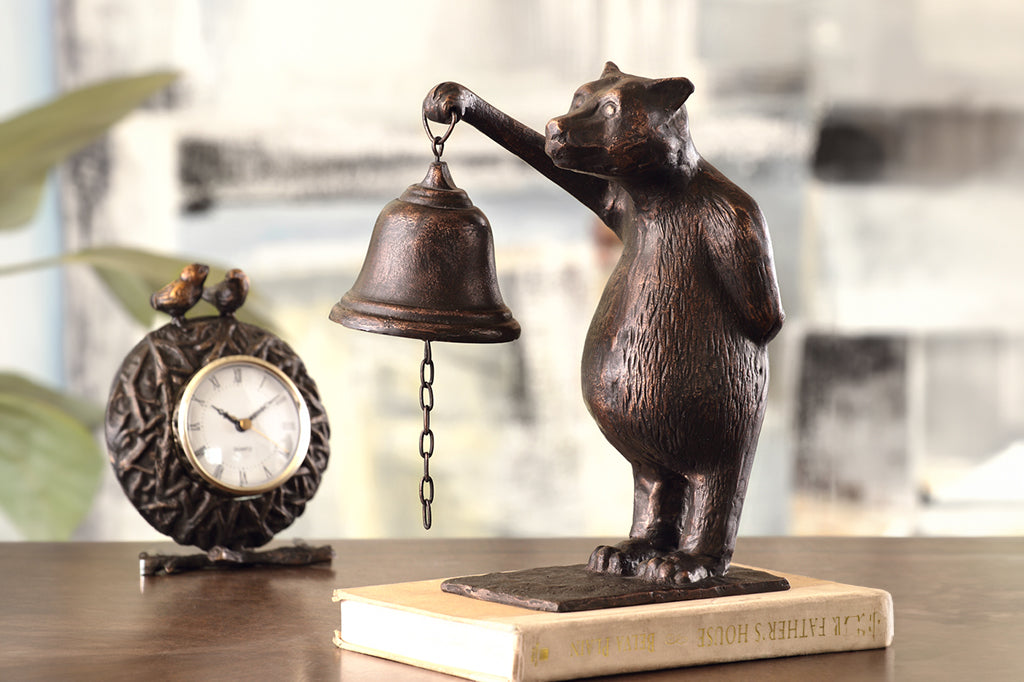 Cast Iron bear holding a bell sculpture set on book in table scene