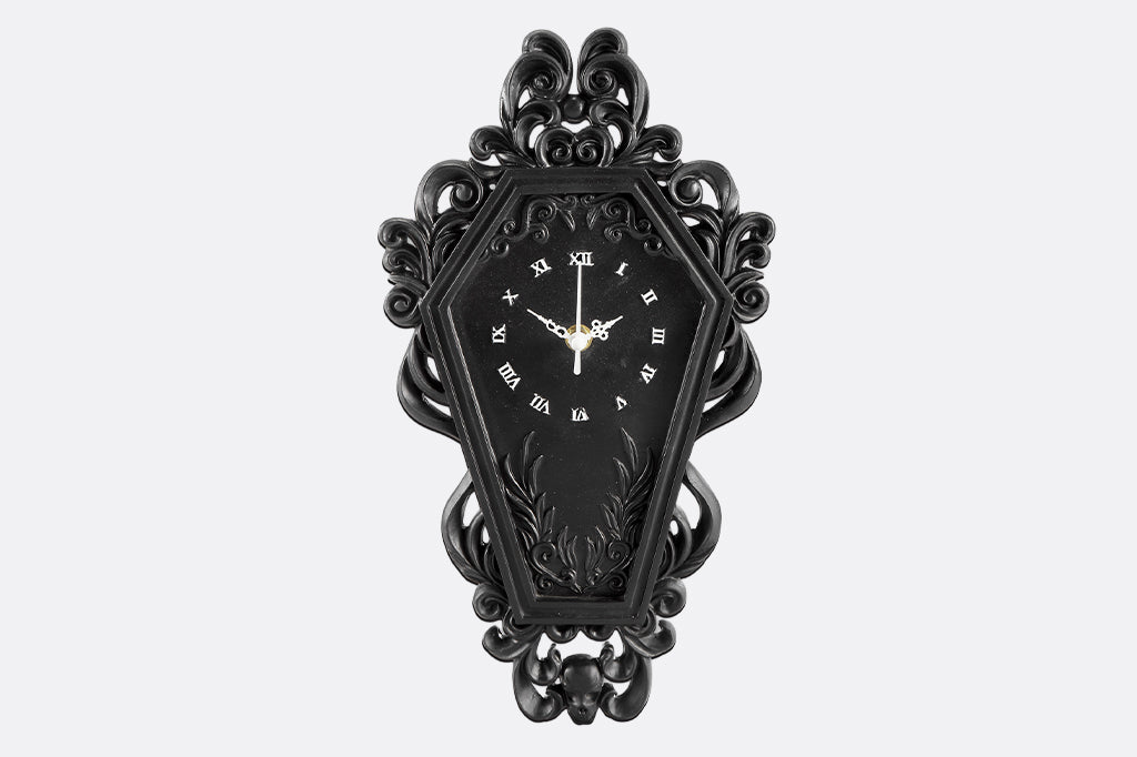 Victorian and gothic inspired coffin-shaped black clock with intricate design on a white background