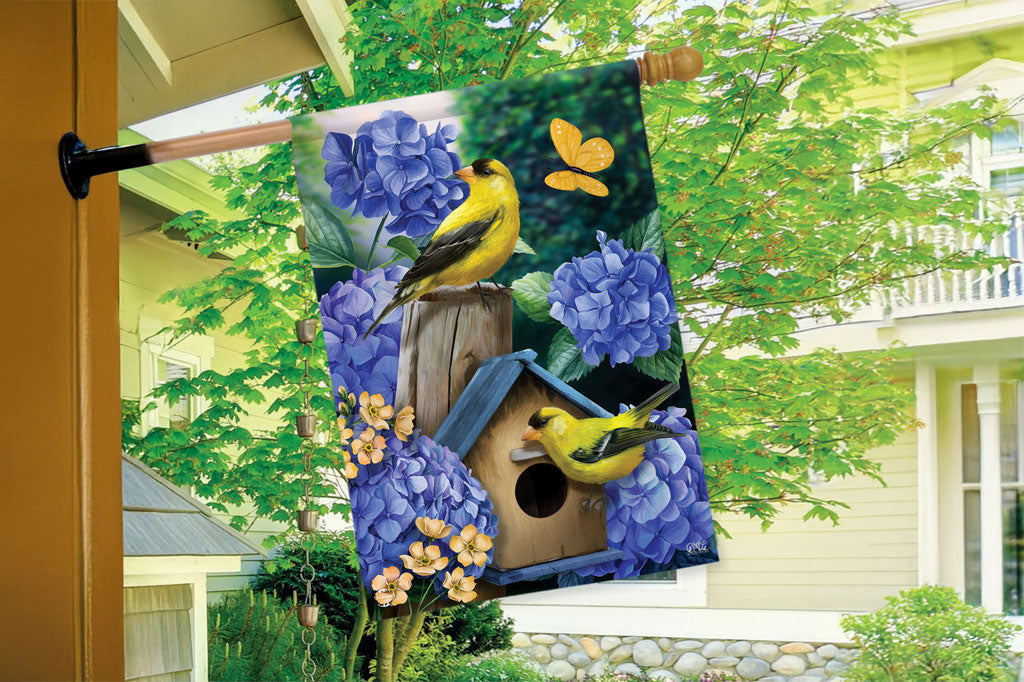 garden flag design of goldfinches and hydrangeas - shown on house flagpole
