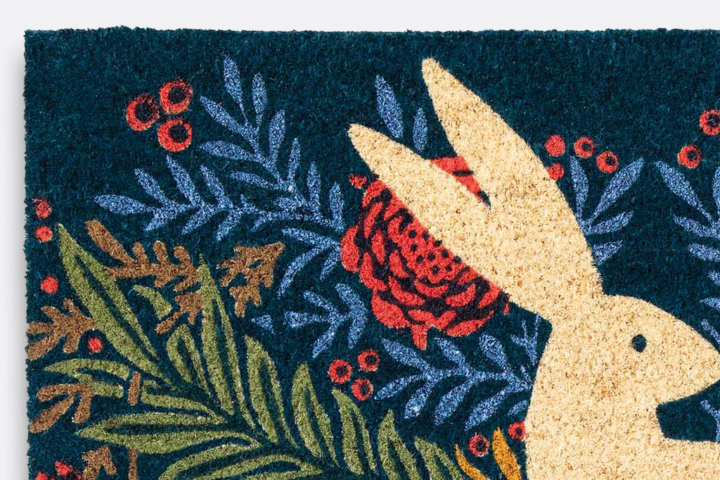 A coir doormat of a bunny on a centered on a floral design.