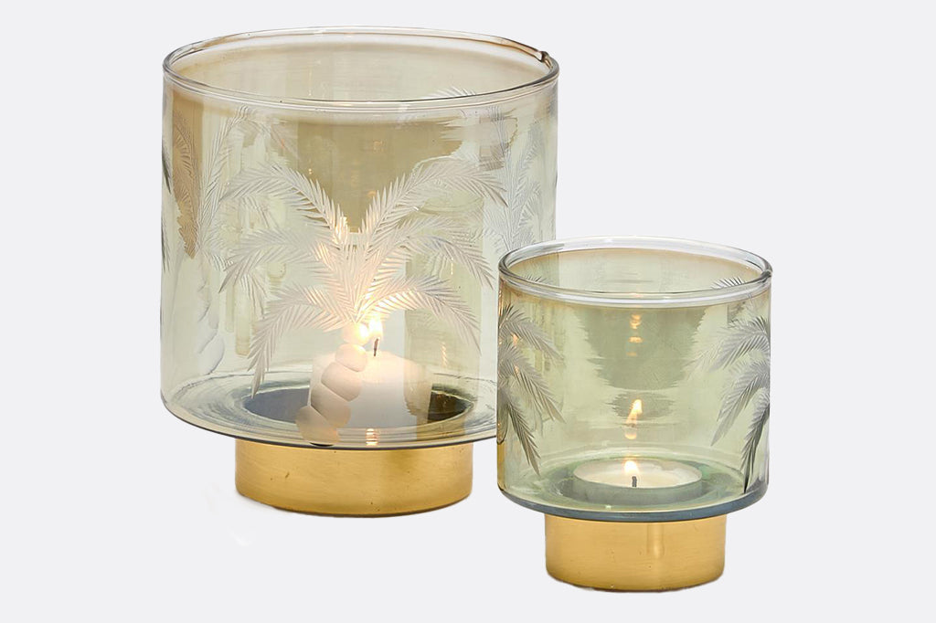 Set of etched palm tree glass candle holders with gold details with lit votive and tealights inside 