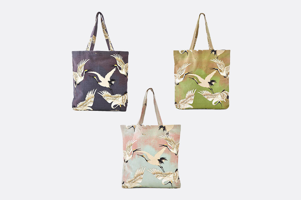 3 tote bags shown together featuring herons in Asian illustration style - charcoal/green/blue backgrounds