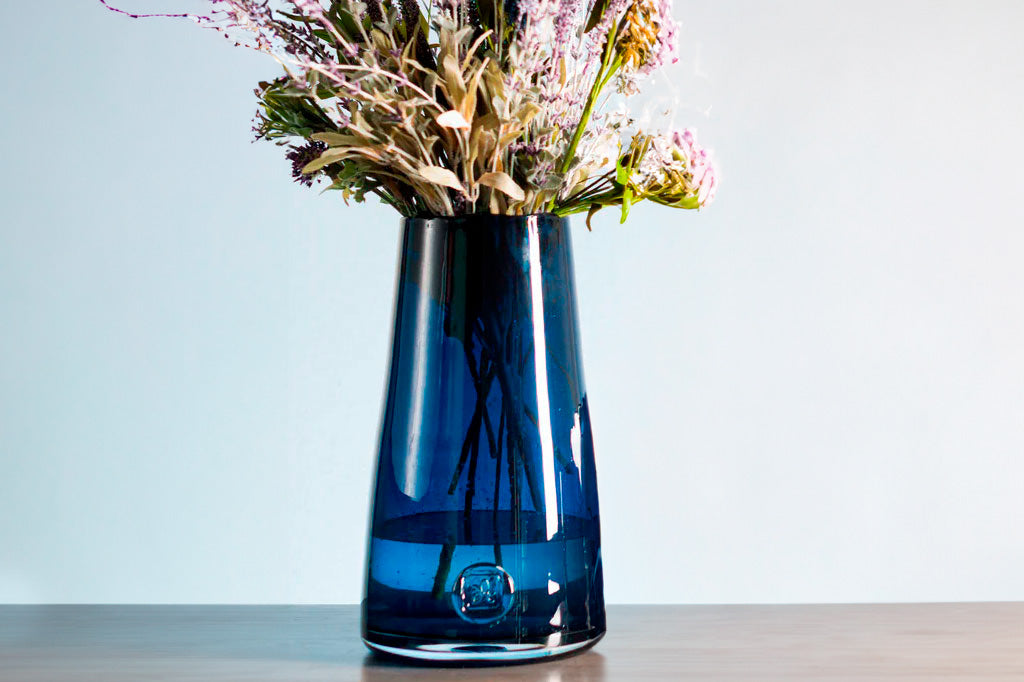 blue glass vase on table with flower arrangement