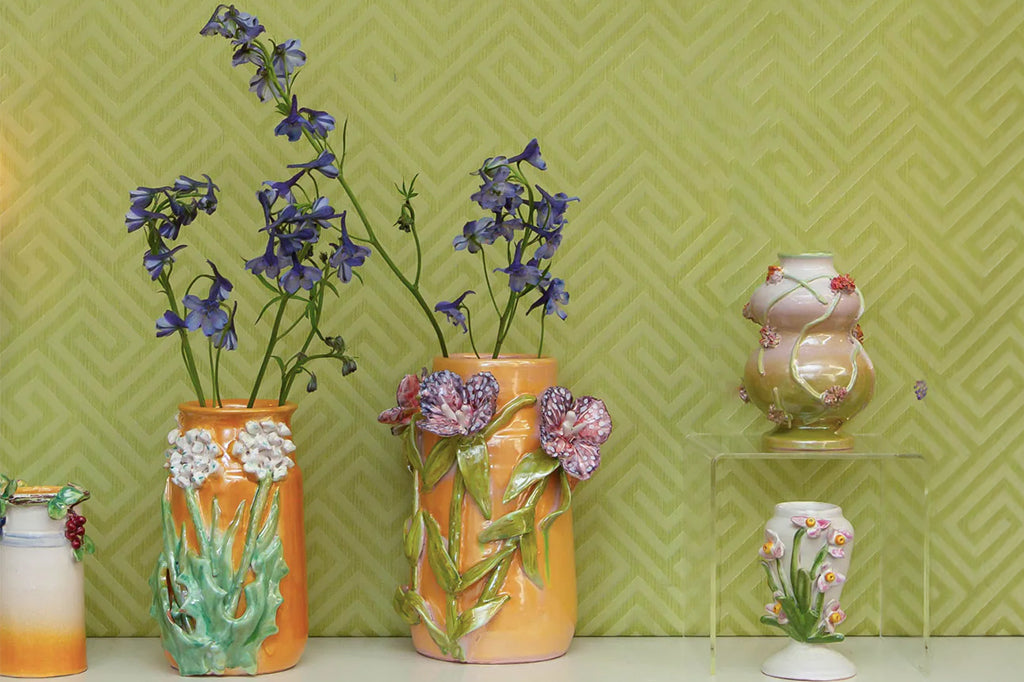 dark purple flowers with white spots 3-d sculptured flower on mango colored wide neck vase 